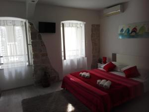 een slaapkamer met een bed met een rode deken en 2 ramen bij Apartman Dražin in Kaštela
