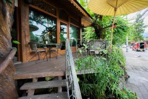 a wooden porch with a table and an umbrella at Mountain View GuesthouseChiangmai in Chiang Mai