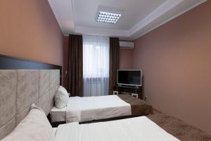a hotel room with two beds and a television at Fedorov ApartHotel Barnaul in Barnaul