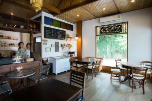 a restaurant with tables and chairs and a woman sitting at a counter at Mountain View GuesthouseChiangmai in Chiang Mai