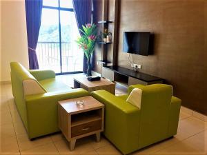 a living room with two green chairs and a television at Sekata Apartment in Cameron Highlands