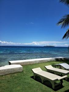 two white chairs sitting on the grass near the ocean at Anton's Beach Resort in Oslob