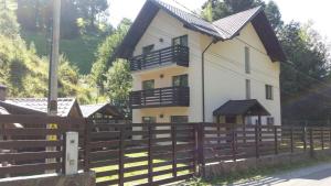 a large white house with a wooden fence at Casa Fulg de Nea in Moieciu de Sus