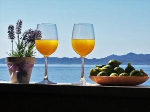 dos copas de vino y un bol de fruta en una mesa en Apartments Anita - Punta Skala, en Petrčane