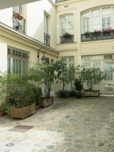 パリにあるAtypique Grands Boulevards CityCosyの鉢植えの植物と窓のある建物の中庭