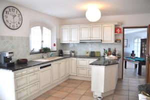 a kitchen with white cabinets and a clock on the wall at Villa 342 m2 classée 4 étoiles sur 1 ha - Provence in Besse-sur-Issole