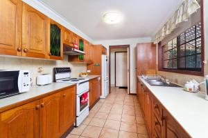 a kitchen with wooden cabinets and white appliances at Byron Bay Accom Marvel St Byron Bay in Byron Bay +1 photo