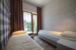 a small bedroom with two beds and a window at Villa Arkadia MARE in Łukęcin