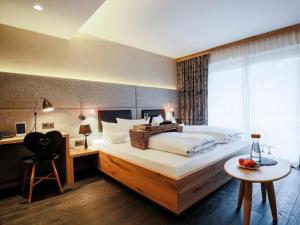 a bedroom with a large bed with a desk and a chair at Staudacherhof in Garmisch-Partenkirchen I Blick aufs Zugspitzmassiv I einzigartige Bayurvida Küche in Garmisch-Partenkirchen +68 photos
