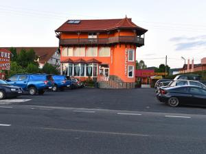 um edifício laranja com carros estacionados num parque de estacionamento em Vila Belvedere em Hateg
