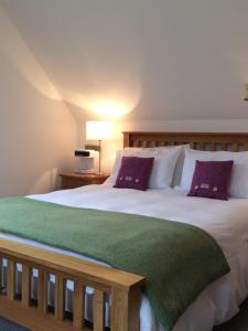 a bedroom with a large white bed with purple pillows at Lochedge Lodge in Bunaveneadar