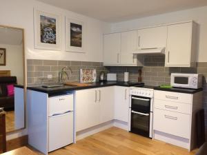 a kitchen with white cabinets and white appliances at Lochedge Lodge in Bunavoneader