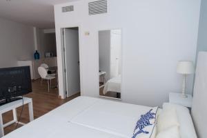 a white bedroom with a white couch and a mirror at Osario in Córdoba