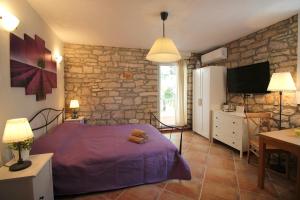 a bedroom with a purple bed and a stone wall at Studio Driovier 11 in Rovinj