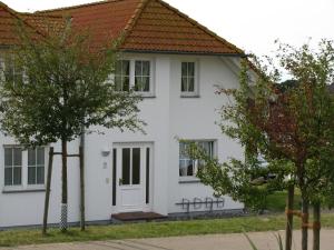 a white house with a red roof at Ferienapartment-ruegen in Neddesitz