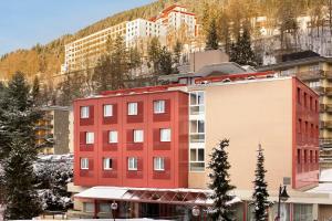 een rood gebouw voor een berg bij Alpine Classic Hotel in Leysin
