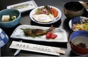 una mesa con platos de comida y tazones de comida en Miharaya Ryokan, en Gujō