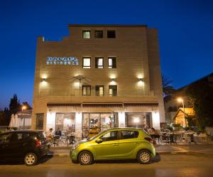 a small green car parked in front of a building at Rafael Residence Boutique in Jerusalem
