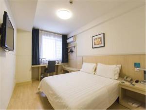 a hotel room with a large bed and a desk at Jinjiang Inn Central Qingdao Hangzhou Road in Qingdao