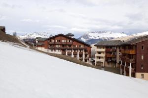 a snowy hill with buildings and mountains in the background at Residence La Marelle et Le Rami - maeva Home in Les Coches