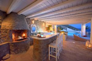 an outdoor kitchen with a stone fireplace and a tub at La Vie In Blue in Ornos