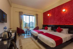 een hotelkamer met 2 bedden en een rode muur bij Tuki Resort in Pokhara