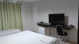 a hotel room with a bed and a desk with a television at Hotel Parnaiba in Timon