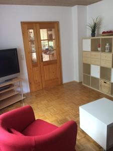 a living room with a red chair and a television at Ferienwohnung Im Grünen in Illschwang