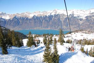 a group of people riding a ski lift on a snow covered mountain at Hotel Brienz in Brienz
