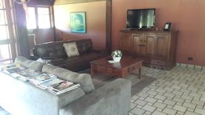 a living room with a couch and a tv at Chácara San Diego - Brotas in Brotas