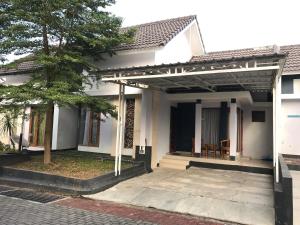 a white house with a porch and a tree at Naura Guest House in Yogyakarta