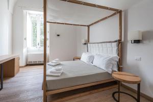 B&B Il Palazzotto Luxury Suites في ليتشي: غرفة نوم مع سرير المظلة وطاولة