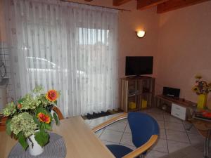 a living room with a table with flowers and a television at Ferienhaus An der Schlossmauer in Oberschwarzach