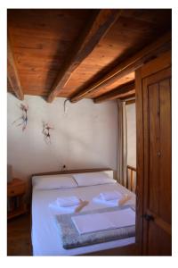 a bedroom with a bed with white sheets and wooden ceilings at Milos Vaos Windmill in Plaka Milou
