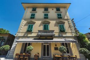 un edificio con tavoli e sedie di fronte ad esso di Hotel Corallo a Montecatini Terme