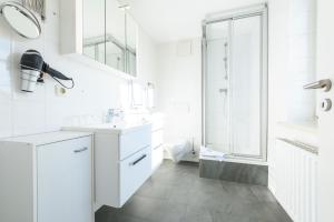 a white bathroom with two sinks and a shower at Hotel Boddenhus Garni in Zingst