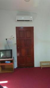 um quarto com uma porta de madeira e uma televisão em NUE Guesthouse em Kota Bharu