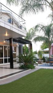 a house with a balcony and a lawn at Cycad Palm Guest House Gaborone in Gaborone