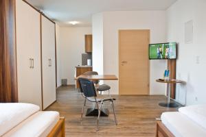 a room with a table and chairs and a tv at greenpartment Boardinghouse Neustadt in Neustadt an der Donau
