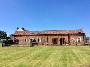 un gran edificio de ladrillo con un campo de hierba delante de él en Grange Farm Cottages, en Wressell