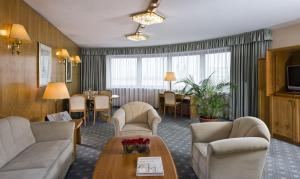 a hotel room with a couch and chairs and a table at Maritim Hotel Magdeburg in Magdeburg