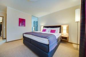 a bedroom with a large bed with pink pillows at R&R Residenzen Aparthotel in Mitterbach