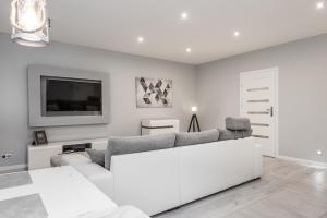 a white living room with a couch and a tv at Apartament Silesian Vip in Zabrze