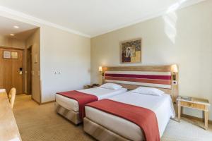 um quarto de hotel com duas camas e uma mesa em Riviera Hotel em Carcavelos