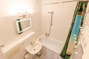 a white bathroom with a sink and a bath tub at Downtown Apartments Unterbilk in Düsseldorf +15 photos