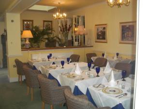 a dining room with tables and chairs with white table cloth at Beech House Hotel in Reading