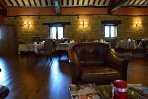 un comedor con mesas y sillas y un sofá de cuero en Hospedería Palacio de Casafuerte en Zarratón