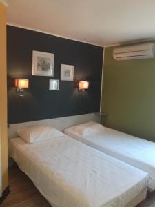 バイヤルグにあるFasthotel Montpellier Baillarguesのベッド2台 壁にランプ2つが備わる客室です。