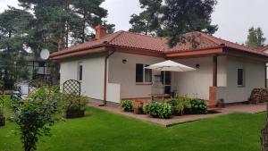 a small white house with an umbrella in a yard at Słoneczny Dom in Poddąbie