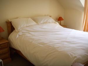 a bed with white sheets and pillows in a bedroom at Cumledge Yew Trees Cottage in Duns